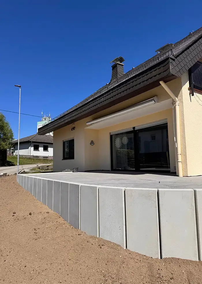 Haus mit großer Terrasse und gelber Fassade unter klarem blauem Himmel